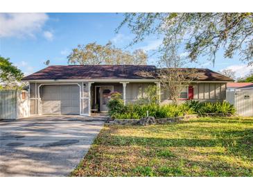 Charming single-Gathering home features a manicured lawn, a gray exterior, and an attached two-car garage at 5741 Riddle Rd, Holiday, FL 34690