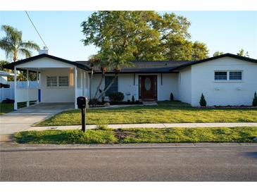 Charming single-story home featuring a well-manicured lawn, brick exterior, and inviting curb appeal at 8412 Stillbrook Ave, Tampa, FL 33615