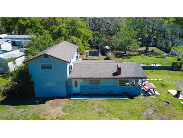 Aerial view of a two-story home with a large backyard and mature trees providing plenty of shade at 10034 Burton St, New Port Richey, FL 34654