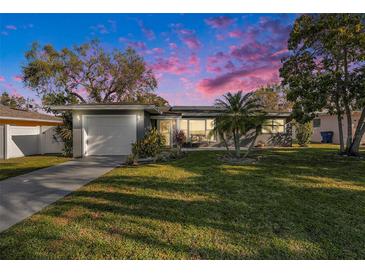 Charming single-story home with a well-manicured lawn and a two-car garage at sunset at 1424 Orange St, Clearwater, FL 33756