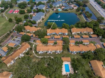 Beautiful aerial view of a condo community with mature landscaping, pool, and access to pond at 1438 Millstream Ln # 201, Dunedin, FL 34698