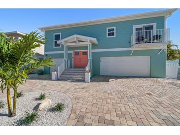 Charming two-story home features a colorful exterior, brick driveway, and well-manicured landscaping at 16109 3Rd E St, Redington Beach, FL 33708