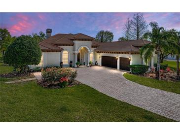 Elegant home exterior featuring lush landscaping, brick driveway, and a neutral color palette at 34201 Kentucky Derby Pl, Dade City, FL 33525