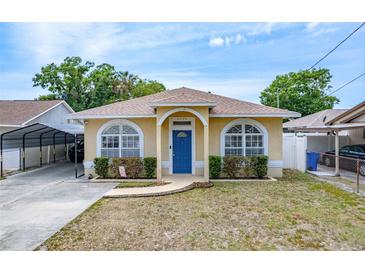 Charming single-story home featuring a blue door, arched windows, and manicured landscaping at 6920 N Hubert Ave, Tampa, FL 33614