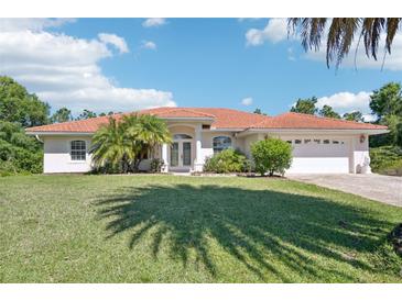 Charming single-story home featuring a red tile roof, well-maintained lawn, and mature palm trees at 6968 De Brita Rd, North Port, FL 34291