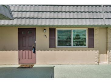 Home exterior featuring a neutral color scheme with a light gray roof and a front door on the left at 1801 Bedford Ter # 221, Sun City Center, FL 33573