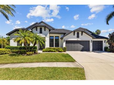 Beautiful two-story home featuring a three-car garage, well-manicured lawn, and lush tropical landscaping at 310 Cockle Shell Loop, Apollo Beach, FL 33572