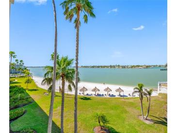Beautiful view of the white sand beach with tiki hut umbrellas and calm water at 5701 Bahia Del Mar Cir # 408, St Petersburg, FL 33715