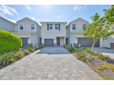 Townhome with gray brick paved driveway, neutral paint color, manicured landscaping and single-car garage at 1022 Orchard Arbour Ct, Tampa, FL 33613