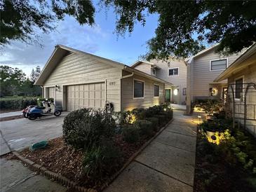 Charming home featuring a two-car garage, lush landscaping and a paver walkway leading to the front door at 1093 Muirfield Ct, Tarpon Springs, FL 34688