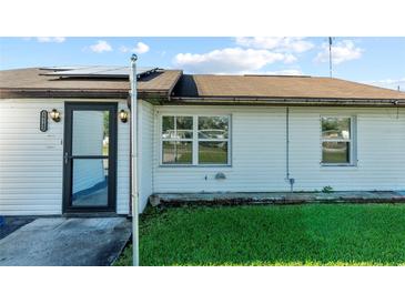 Charming exterior view showcasing the home's white siding, black front door, and well-maintained lawn at 39142 Kendell Dr, Zephyrhills, FL 33542