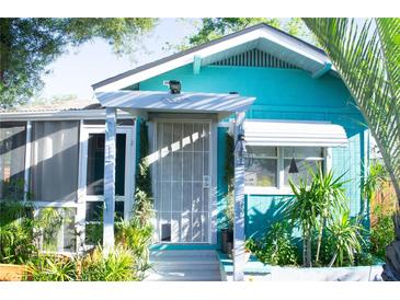 Charming turquoise home with a screened porch, decorative security door, and lush tropical landscaping at 2501 Emerson S Ave, St Petersburg, FL 33712