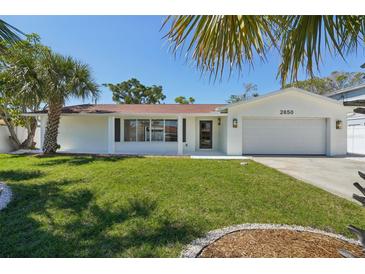 Charming single-story home featuring a well-manicured lawn, a white exterior, and tropical landscaping at 2650 E Vina Del Mar Blvd, St Pete Beach, FL 33706