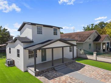 Inviting two-story home with a covered front porch and a beautifully paved driveway and well maintained lawn at 2930 W Arch St, Tampa, FL 33607