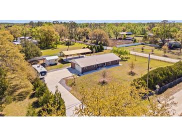 Aerial view of a property showcasing the house, additional structures, and surrounding land at 8122 Ehren Cemetery Rd, Land O Lakes, FL 34639