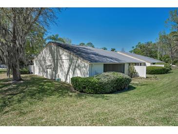 Quaint single-story home featuring a well-manicured lawn and a screened-in porch for enjoying the outdoors at 1333 Shady Pine Way # F, Tarpon Springs, FL 34688