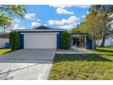 Charming single-story home featuring a two-car garage and well-manicured landscaping, painted in a serene blue hue at 6208 Imperial Ky, Tampa, FL 33615