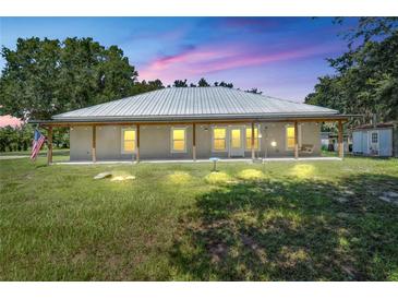 Charming home featuring a metal roof, covered porch, and a well-maintained lawn at dusk at 9017 S County Line Rd, Lithia, FL 33547
