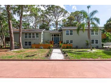 Two-story home features a manicured lawn, turquoise doors, and a symmetrical facade at 1320 Coral S Way, St Petersburg, FL 33705