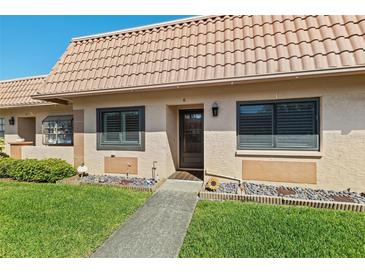 Inviting front exterior with a tiled roof, landscaping, and charming walkway leading to the front door at 19029 Us Highway 19 N # 27E, Clearwater, FL 33764