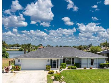 Charming single-story home with well-manicured lawn and lush landscaping located on a waterfront property at 22322 Tennyson Ave, Port Charlotte, FL 33954