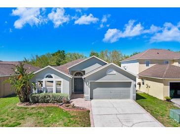 Charming single-story home featuring a well-maintained lawn, mature landscaping, and attached two-car garage at 24941 Ravello St, Land O Lakes, FL 34639