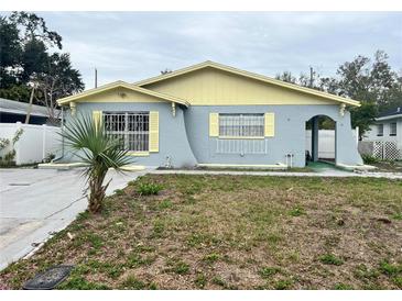 Charming single-story home featuring a light blue exterior with yellow accents and a cozy front yard at 2944 W Beach, Tampa, FL 33607