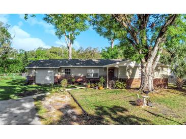 Charming one-story home features a well-manicured lawn and mature shade trees, a brick facade, and a front entrance at 6754 Ralston Beach Cir, Tampa, FL 33614