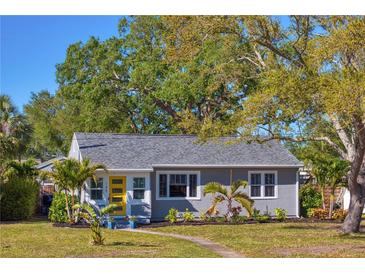 Charming single-story home featuring a yellow door, manicured lawn and mature trees at 145 38Th Ne Ave, St Petersburg, FL 33704