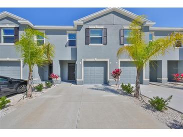 Beautiful townhome showcasing a two-story exterior, grey paint, shuttered windows, and a two-car garage at 1504 Colt Creek Pl, Wesley Chapel, FL 33543