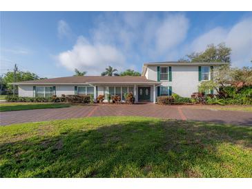 Charming two-story home with white brick, green shutters, and a spacious brick driveway at 7922 Spring Valley Dr, Tampa, FL 33615