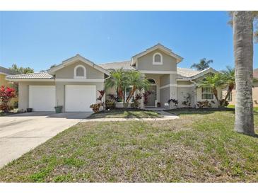 Charming single-story home featuring a three-car garage, lush landscaping, and a neutral color palette at 954 Cobblestone Ln, Tarpon Springs, FL 34688
