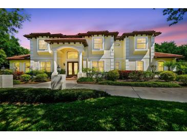 Elegant home with a red tile roof, cream-colored stucco, manicured lawn, and columns at the entryway at 17003 Madres De Avila, Tampa, FL 33613