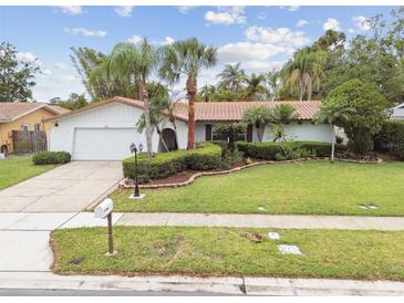 Charming single-story home featuring a well-manicured lawn, mature landscaping, and a classic red tile roof at 1870 Wateroak W Dr, Clearwater, FL 33764
