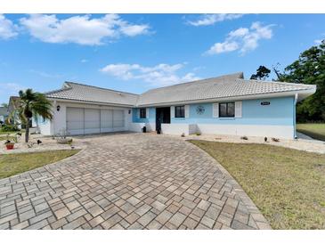 Charming blue single-story home with a brick driveway and well-maintained landscaping at 1929 New Bedford Dr, Sun City Center, FL 33573