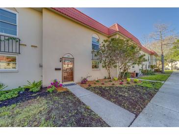 Inviting condo exterior featuring a red tile roof, well-maintained landscaping, and an accessible walkway leading to the front door at 2700 Bayshore Blvd # 1E, Dunedin, FL 34698