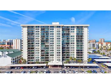 High-rise building with multiple balconies and a parking lot, set against a blue sky at 400 Island Way # 1708, Clearwater Beach, FL 33767