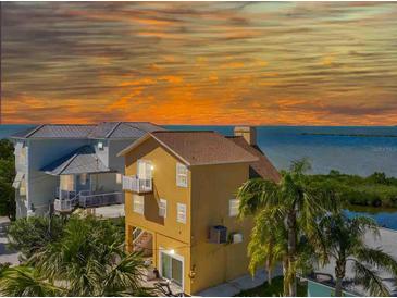 Charming multi-story home with a balcony, palm trees, and a picturesque waterfront view at sunset at 6633 Driftwood Dr, Hudson, FL 34667