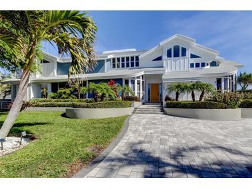 Stunning two-story home with manicured landscaping and a brick driveway, enhancing its curb appeal at 103 Morgan Dr, Belleair Beach, FL 33786