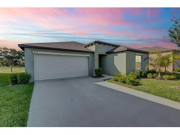 Charming single-story home with a two-car garage, well-maintained lawn, and inviting curb appeal under a colorful sky at 6727 Bar S Bar Trail, Zephyrhills, FL 33541