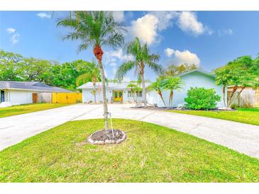 Charming single Gathering home featuring lush landscaping and a well-manicured lawn at 921 Woodland Dr, Palm Harbor, FL 34683