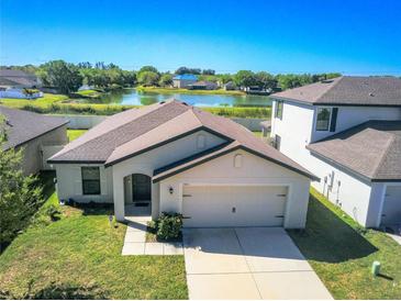 Charming single-story home with a two-car garage and a well-maintained lawn, backing up to a tranquil lake at 1001 Culbreath Green Ct, Ruskin, FL 33570