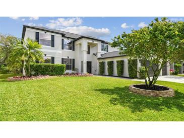 Beautifully landscaped front yard with lush lawn and meticulously maintained hedges complements the home's architecture at 16323 Muirfield Dr, Odessa, FL 33556