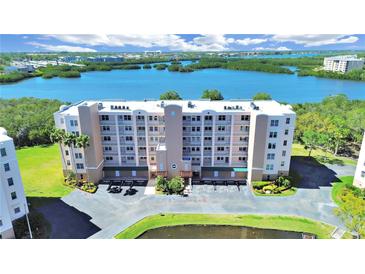 Aerial view of a seven-story condo building surrounded by lush landscaping and a serene waterfront at 6495 Shoreline Dr # 8105, Seminole, FL 33708
