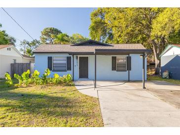 Charming single-story home featuring a covered front porch, blue siding, and mature trees at 6672 56Th N Ave, St Petersburg, FL 33709
