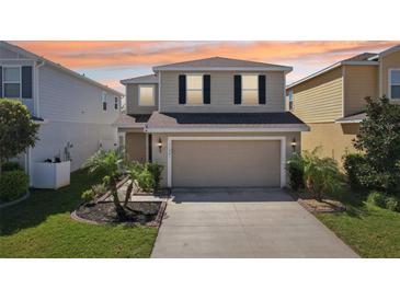 Two-story home with a large garage, well-kept lawn, and decorative landscaping enhancing its curb appeal at 11301 Hudson Hills Ln, Riverview, FL 33579