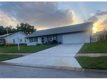 Charming single-story home with a well-maintained lawn and a large driveway leading to an attached two-car garage at 1660 Caledonia Dr, Palm Harbor, FL 34684