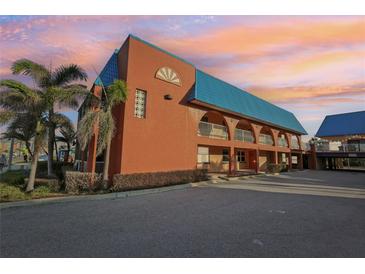 Charming building featuring unique architectural details, a blue roof, and a spacious parking area at 17035 Gulf Blvd # 202, North Redington Beach, FL 33708