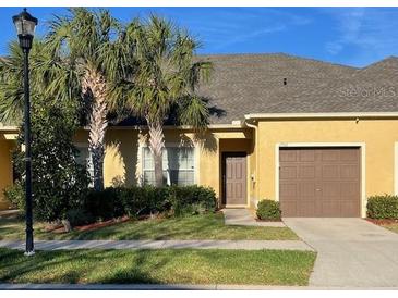 Charming townhome featuring a well-maintained lawn, palm trees, and a single-car garage at 1706 Trailwater St, Ruskin, FL 33570