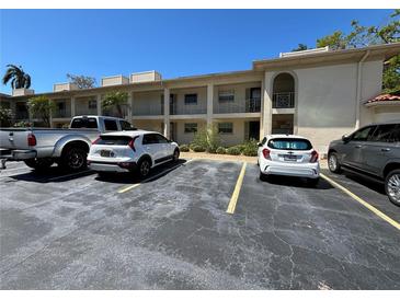 Apartment building featuring a parking lot with multiple parked vehicles on a sunny day at 19029 Us Highway 19 N # 2-12, Clearwater, FL 33764